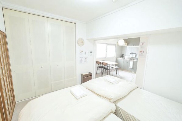 Un dormitorio con cama, armario y una pequeña cocina.