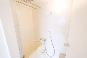 Ein Badezimmer mit Badewanne, Dusche und einer Tür.