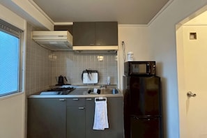 A compact kitchen with a microwave, sink, and cabinets.