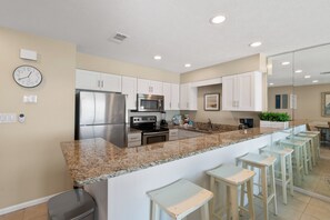 A modern kitchen with stainless steel appliances, a granite countertop, and white cabinetry. - Crystal Villas B9 New Listing Specials! Gulf Front, Pool, Free Beach Service (Destin)
