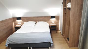 Een slaapkamer met een bed, twee nachtkastjes, een kledingkast en een wandplank.