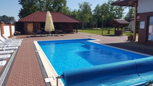 A swimming pool with lounge chairs and a covered seating area. - Azretreat (gmina Ostrowite)