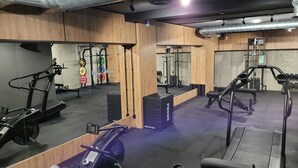 A gym with treadmills, a rowing machine, and weightlifting equipment. - Azretreat (gmina Ostrowite)