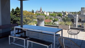 An outdoor patio area with a wooden ceiling, a white table with benches, and a black chair. - Second home Lujan (Luján)
