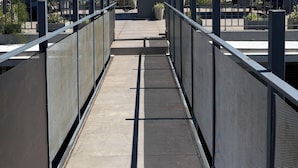 Un pont cobert per a vianants, amb baranes metàl·liques i un camí de formigó.