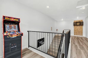 Une pièce équipée d’une console de jeux, d’un escalier et d’un jeu de fléchettes.