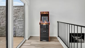 A hallway with a game machine labeled 'Mortal Kombat' and a stone wall. - The Grand Retreat - Brand New! (Hurricane)