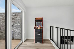 A hallway with a game machine labeled 'Mortal Kombat' and a stone wall. - The Grand Retreat - Brand New! (Hurricane)