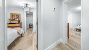 A hallway with a bed, a dresser, and a painting on the wall. - La Casita - Stay for 6 Guests (Tampa)
