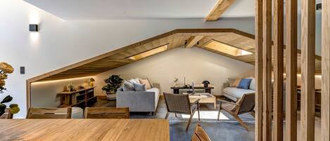A modern loft with exposed wooden beams, a dining area, and a cozy seating arrangement.