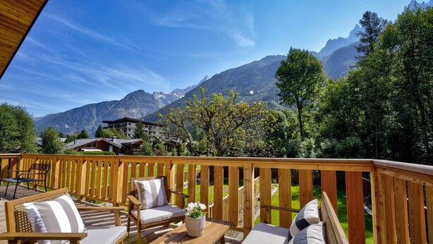 Eine Holzterrasse mit Gartenmöbeln, einem Tisch und einem Blumentopf.