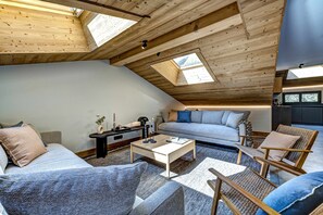 A loft-style living space with a sloped ceiling, skylights, a sofa set, a coffee table, and a wicker chair. - Chalet du Cristal Blanc, Ski, Chamonix All Year (Chamonix)