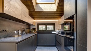 Eine moderne Küche mit Dachfenster, Einbaugeräten und Blick durch das Fenster.