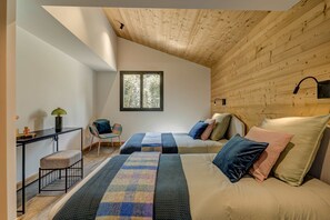 A cozy bedroom with a sloped ceiling, a window, a bed with multiple pillows, a bedside table, and a chair. - Chalet du Cristal Blanc, Ski, Chamonix All Year (Chamonix)