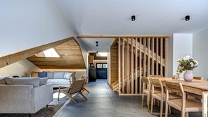 Ein moderner Loft-Wohnraum mit Essbereich, Holzbalkendecke und einer Küche im Hintergrund.