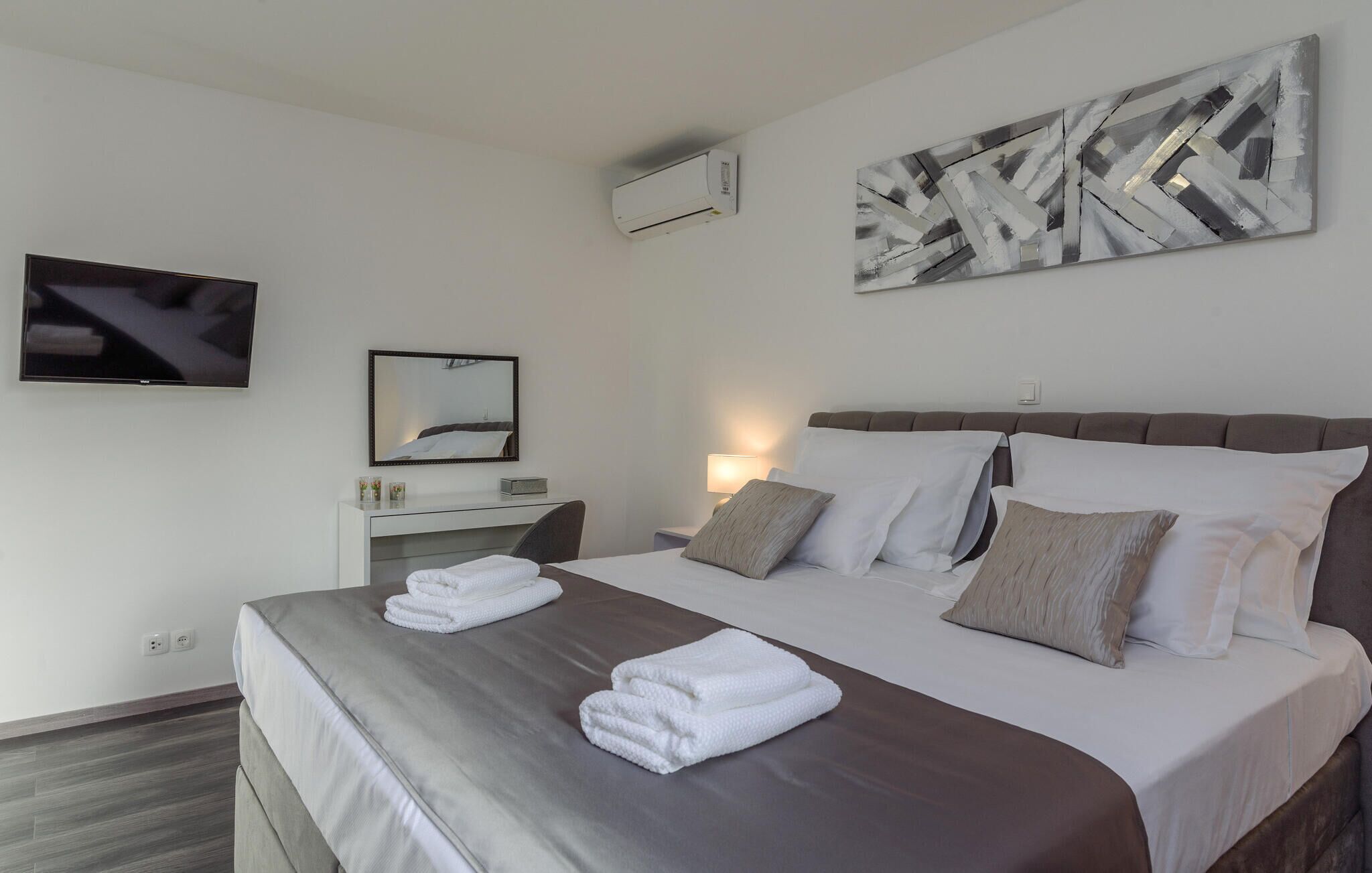 Ett modernt hotellrum med en stor säng, en platt-TV, ett nattduksbord och en väggmonterad luftkonditioneringsanläggning.