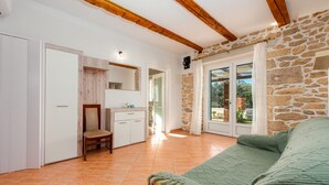A bedroom with a bed, a chair, a wardrobe, a mirror, and a stone wall. - Villa Zdravko Zadarvillas (Škabrnja)