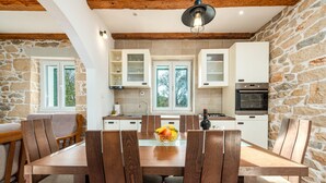 A modern kitchen with stone walls, wooden furniture, and a central island with fruit. - Villa Zdravko Zadarvillas (Škabrnja)