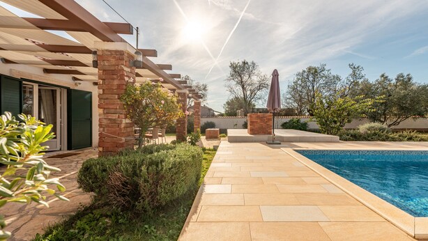 A poolside area with a pergola, brick pillars, and a tiled patio. - Villa Zdravko Zadarvillas (Škabrnja)