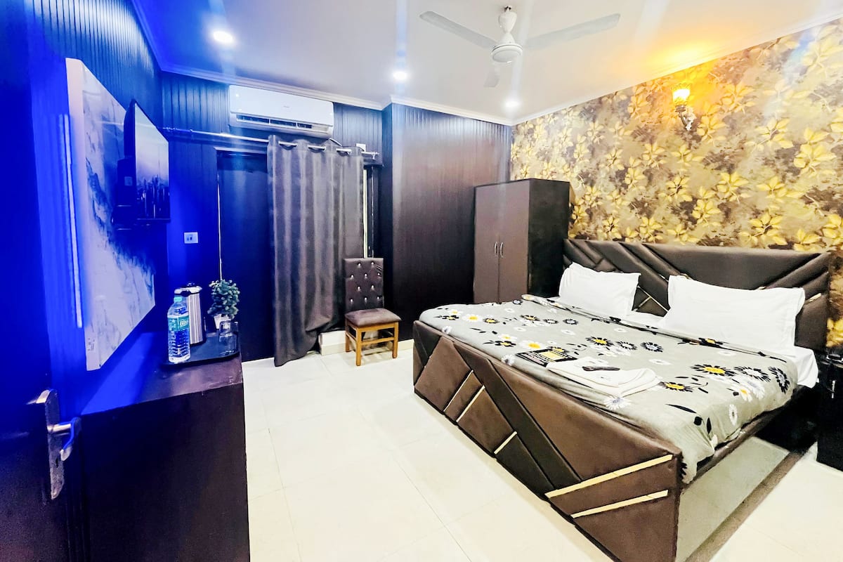 Een moderne slaapkamer met een bed, een plafondventilator, een airconditioningapparaat, een kledingkast en een decoratieve wand.