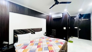 A modern bedroom with a large bed, a ceiling fan, and an air conditioning unit. - Roomshala Hotel Tom & Jerry (New Delhi)