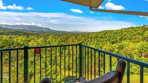 A balcony with a view of a forested mountain range.