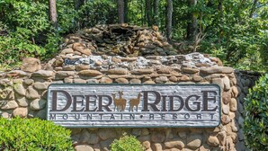 A sign for Deer Ridge Mountain Resort with a stone wall and a small waterfall.