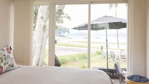 A hotel room with a bed, a window with a view of a parking area and outdoor seating.