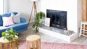 A living room with a blue sofa, a white fireplace, and two red skis mounted on the wall.