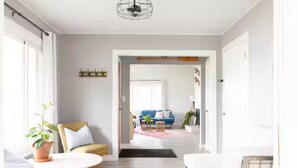 A modern living room with a sofa, armchair, and a coffee table. There is a door leading to another room.