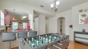 A modern kitchen with a foosball table, bar area, and a dining space with bar stools. - San Antonio Area Home w/ Deck, 14 Mi to Dtwn! (San Antonio)