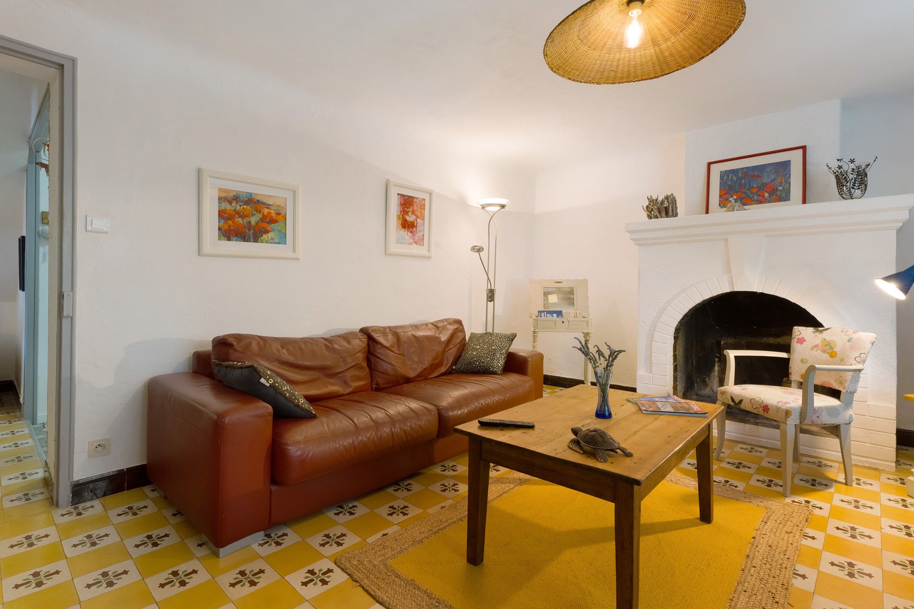 Ein Wohnzimmer mit braunem Ledersofa, einem Holztisch, einem Kamin und einem gemusterten Boden.