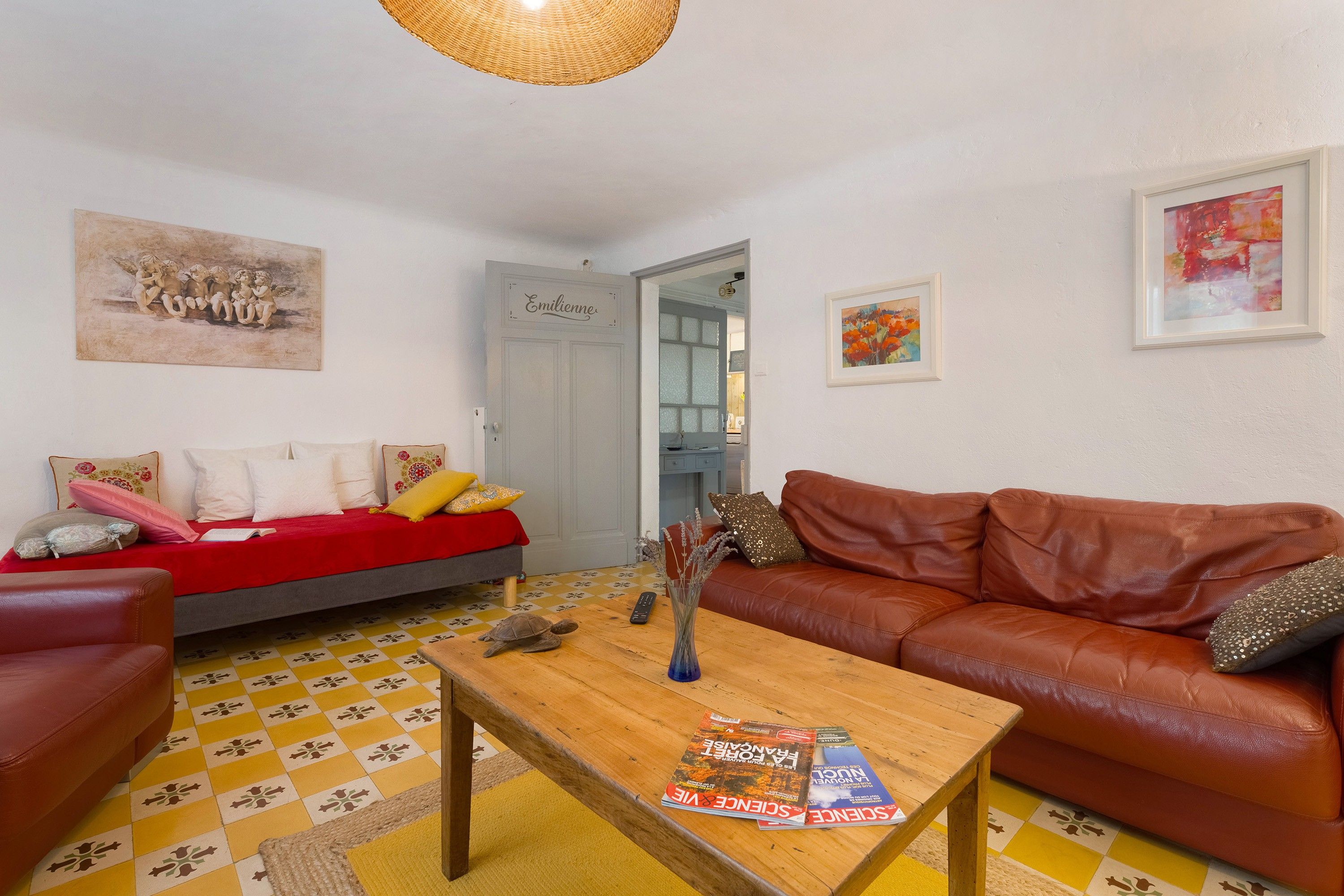 A living room with a red sofa, a brown leather couch, a wooden coffee table, and a tiled floor.