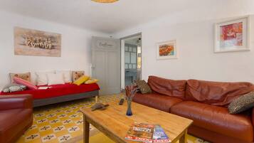 A living room with a red sofa, a brown leather couch, a wooden coffee table, and a tiled floor.