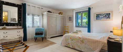 Quarto com cama, cadeira, guarda-roupa, espelho e janela com cortinas.
