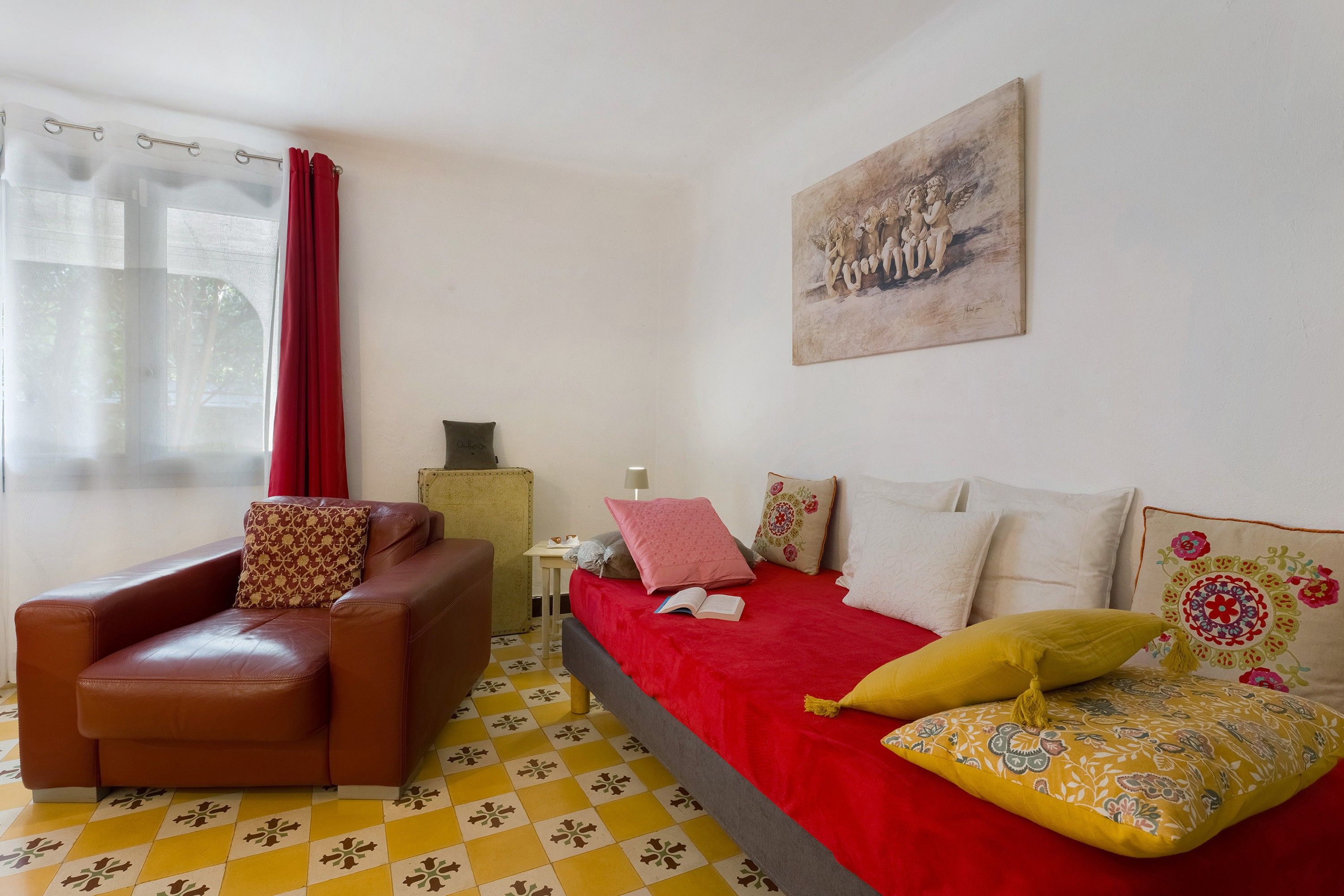 Quarto com cama, cadeira, mesa e um quadro na parede.