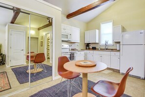 A compact kitchen with white cabinets, a microwave, and a refrigerator. There is a dining area with a round table and two chairs. - Walkable Studio 1 Mi to Riverwalk & Dtwn Bradenton (Bradenton)
