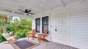 Eine überdachte Veranda mit Holzbänken, einem Tisch und einem Deckenventilator.