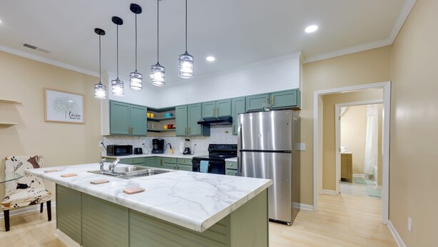 A modern kitchen with a central island, green cabinets, stainless steel appliances, and pendant lighting. - < 10 Mi to Uab: Birmingham Group Getaway (Birmingham)