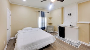 A bedroom with a bed, a ceiling fan, a white dresser, a black appliance, and a white brick wall. - < 10 Mi to Uab: Birmingham Group Getaway (Birmingham)