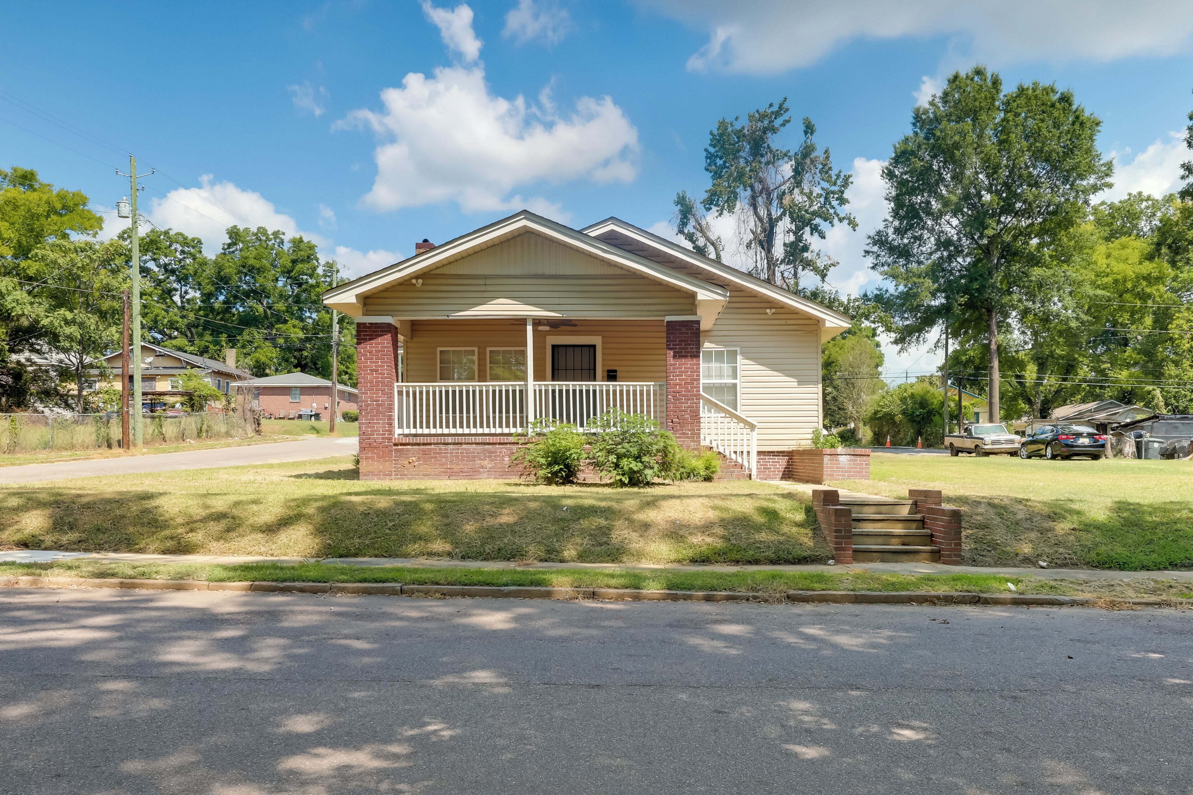 A single-story house with a front porch, brick foundation, and a small front yard.