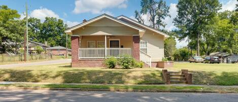 A single-story house with a front porch, brick foundation, and a small front yard.