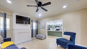 A living room with a fireplace, a ceiling fan, and a kitchen area visible through an open doorway. - < 10 Mi to Uab: Birmingham Group Getaway (Birmingham)