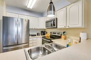 Una cocina moderna con electrodomésticos de acero inoxidable, microondas integrado y pileta doble.