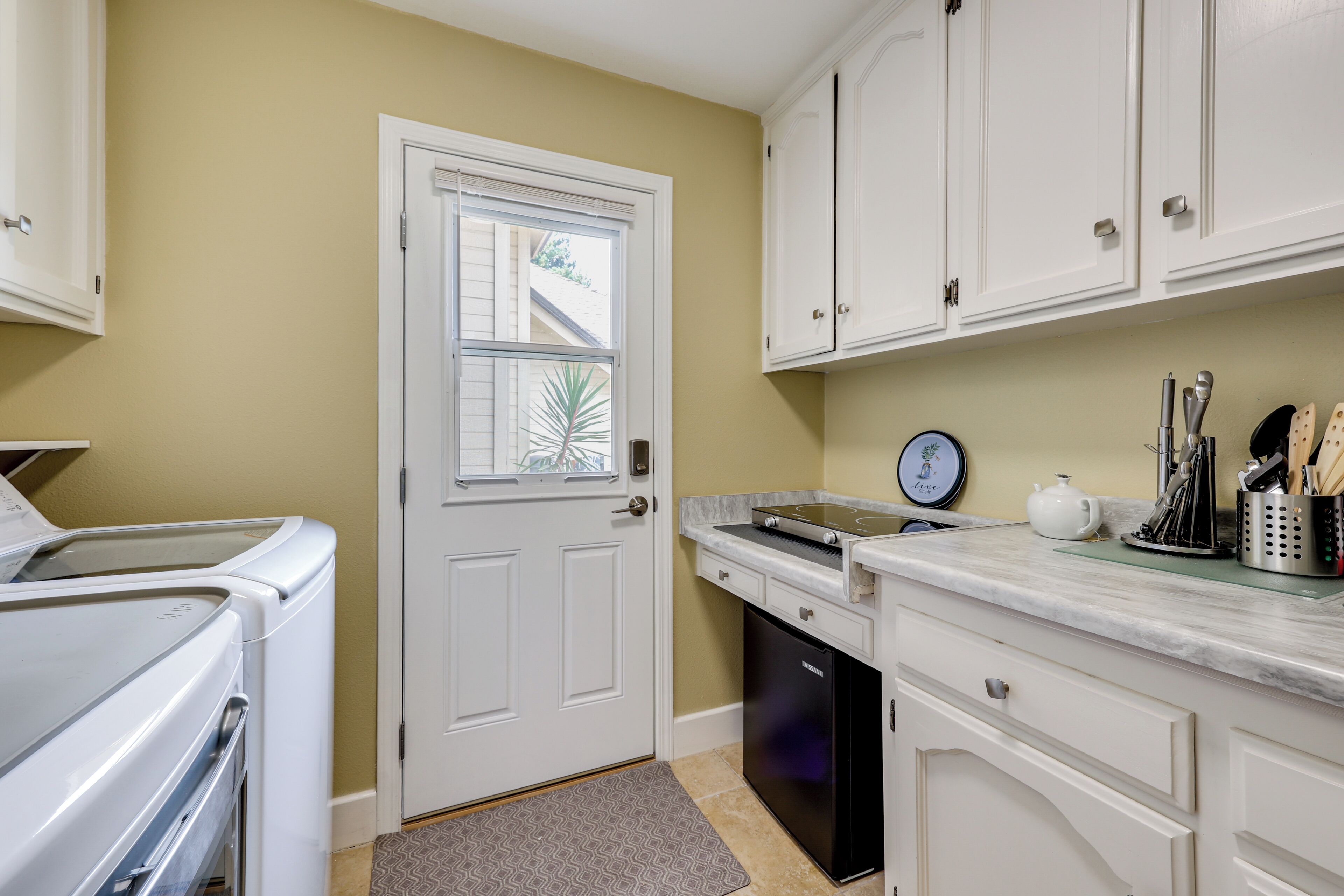 A kitchen with white cabinets, a dishwasher, a countertop with a tea pot, and a clock. - Golf, Hike, Explore: Apt 9 Mi to Dtwn Fresno! (Fresno)