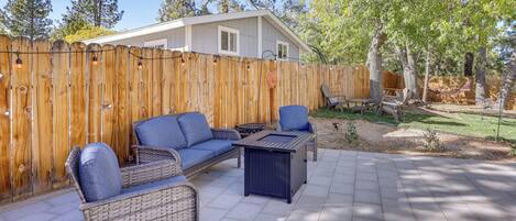 Un patio con mobiliario de mimbre, una mesa y una cerca de madera.
