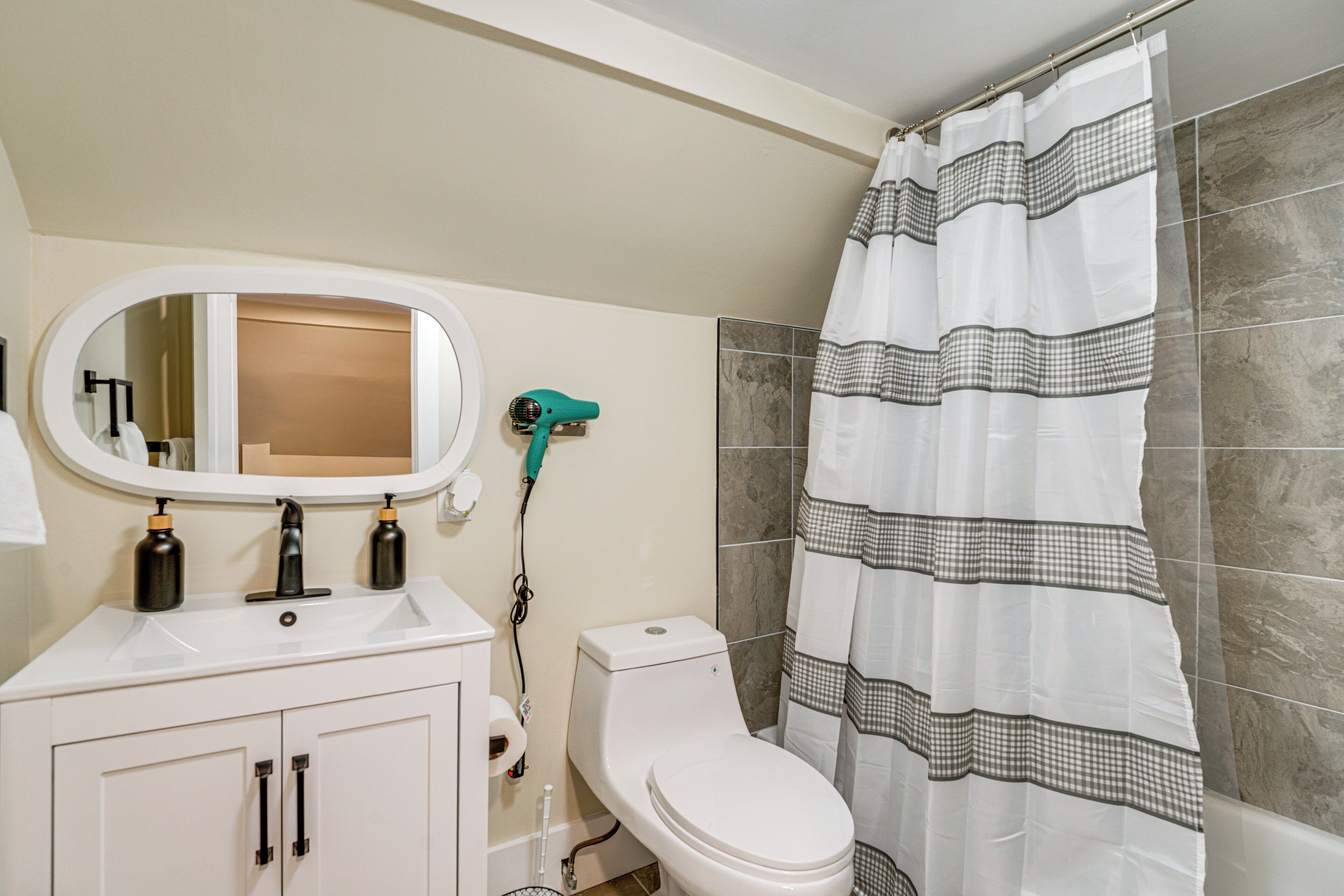 A bathroom with a white sink, mirror, and toilet, a towel rack, and a shower curtain.