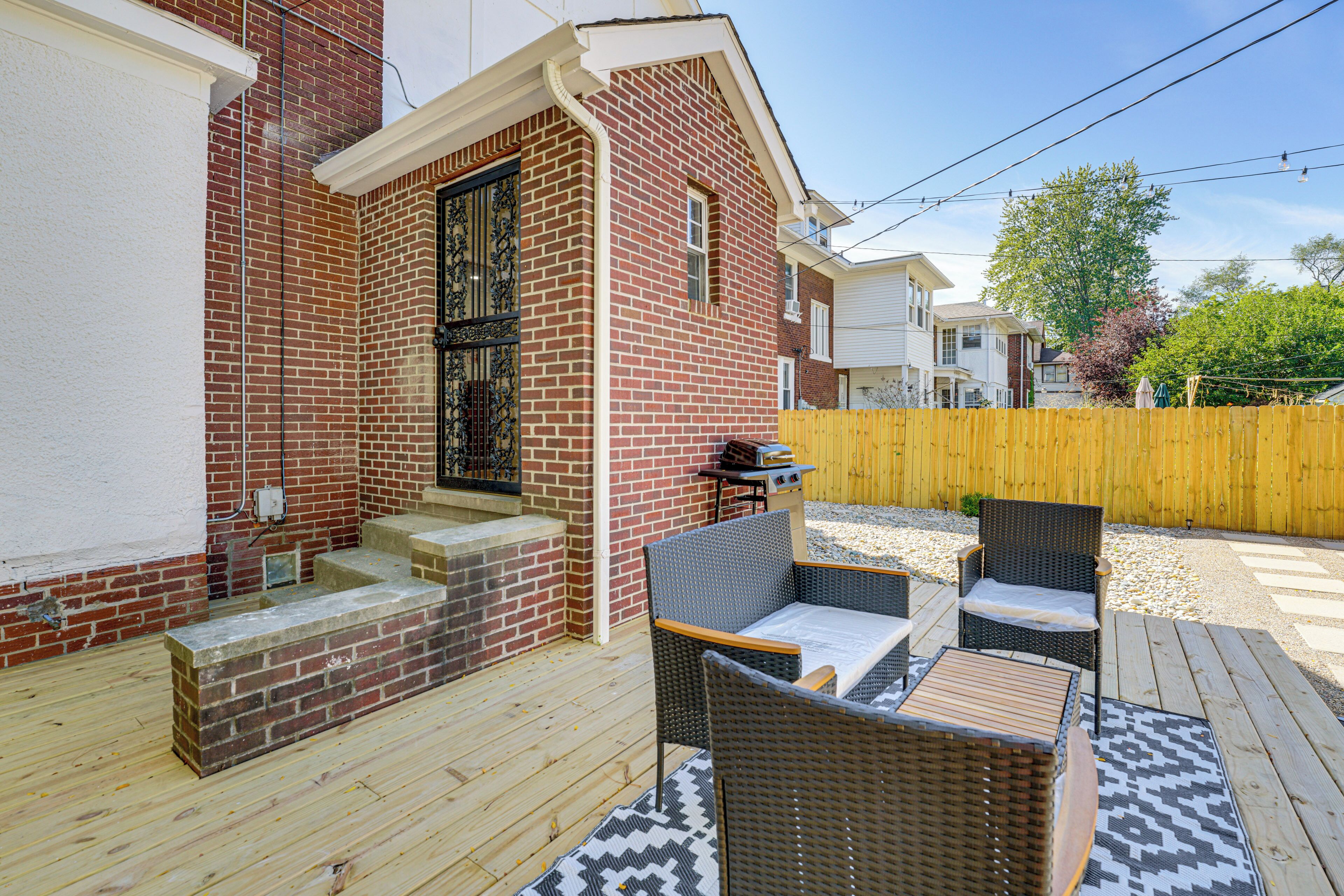A patio area with wicker furniture, a brick wall, and a wooden deck.