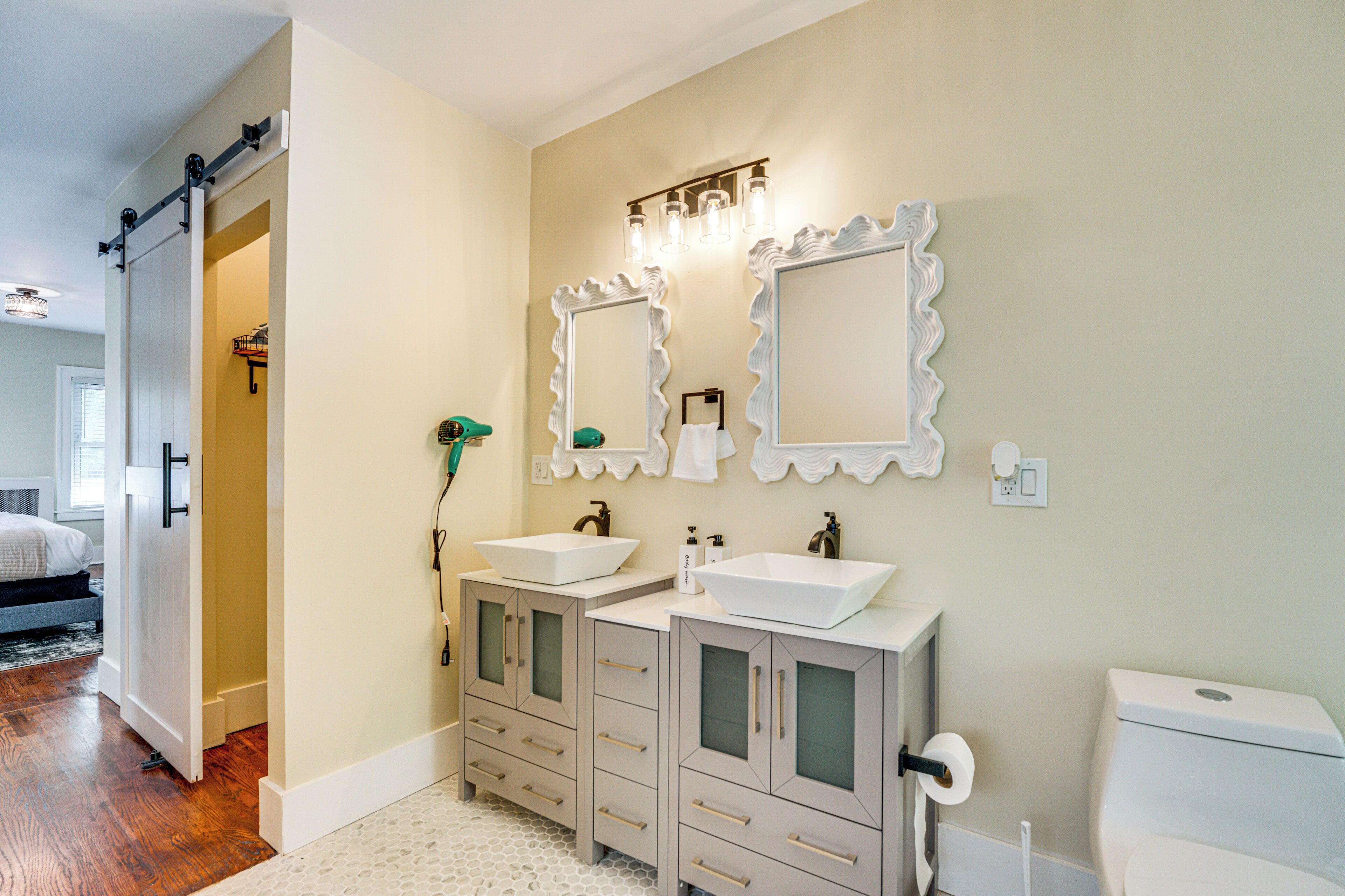 A bathroom with two sinks, a toilet, and a mirror.