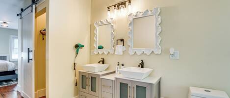 A bathroom with two sinks, a toilet, and a mirror.